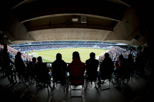 Rullstolsburna åskådare tittar på fotbollsmatchen i