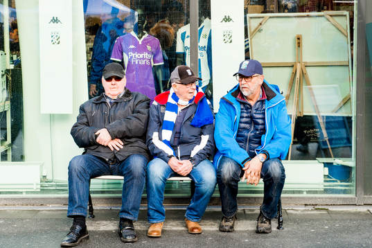 Tre supportrar på en bänk