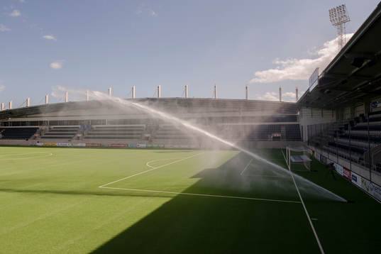 Vattenspridaren på planen före fotbollsmatchen i