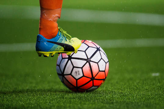 En fotbollssko och boll på konstgräs
