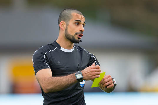 Domare Mohammed Al-Hakim ger en spelare gult kort