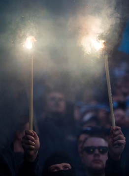 En supporter i Djurgårdens klack håller upp två eldar