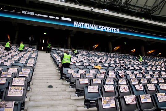 Publikvärdar placerar ut reklamblad på läktaren