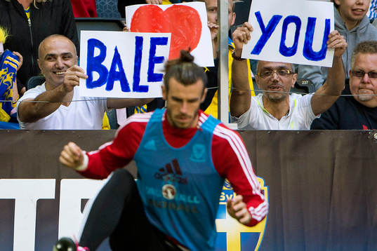 Två supportrar håller upp skyltar bakom Wales Gareth Bale