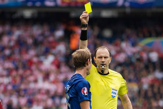 domare Jonas Eriksson delar ut ett gult kort