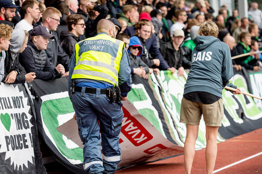 Ordningsvakt plockar upp skyltar nedsparkade av GAIS