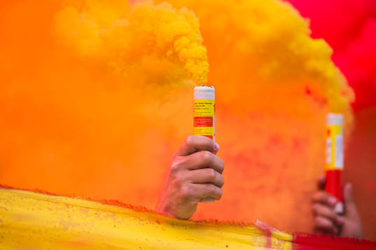 En supporter håller upp pyroteknik innan fotbollsmatchen i