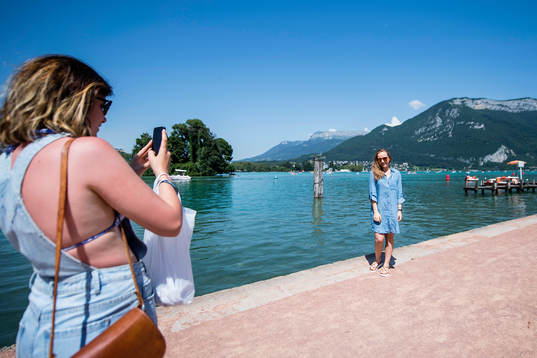 En tjej tar en bild av sin vän vid Lake Annecy där Island