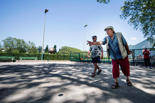 Pensionärer spelar boule på en boulebana vid Lake Annecy