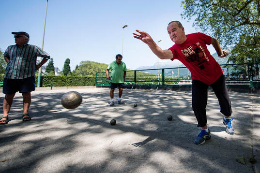 Pensionärer spelar boule på en boulebana vid Lake Annecy