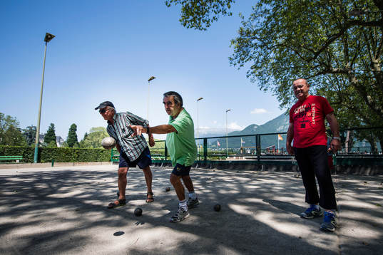 Pensionärer spelar boule på en boulebana vid Lake Annecy