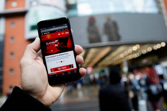 En man läser United nyheter på mobilen