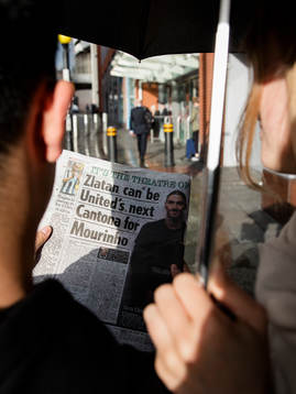 Ett par som läser ett engelskt tidningsuppslag med Zlatan