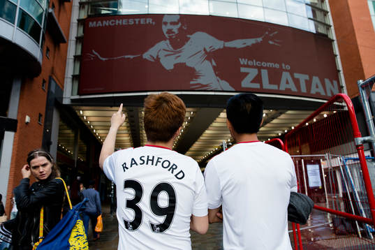 Två united supportrar kollar in en stor skärm med Zlatan
