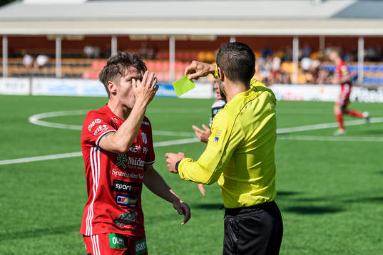 s James Burgin får gult kort av Domare Ozan Camlibel