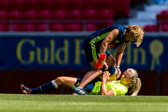 Stina Blackstenius får hjälp med stretching av Sveriges