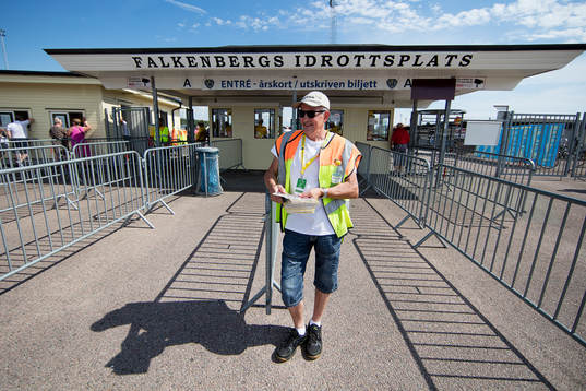 En funktionär delar ut programblad utanför entrén