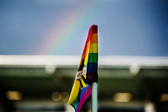 En hörnflagga med pridefärgerna och bakom syns en