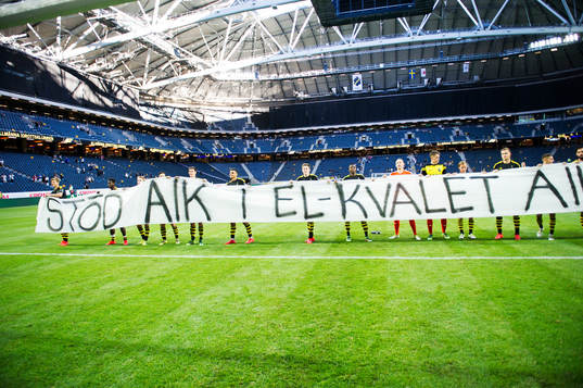s spelare rullar ut en banderoll som säger "stöd AIK i