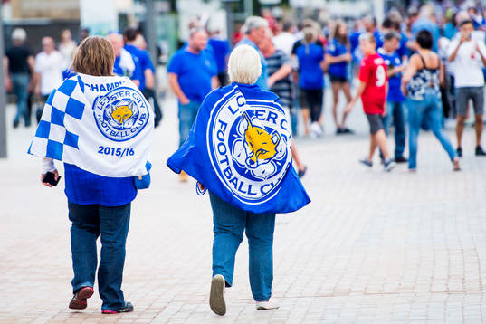 Två Leicester City supportrar med klubbens flaggor på