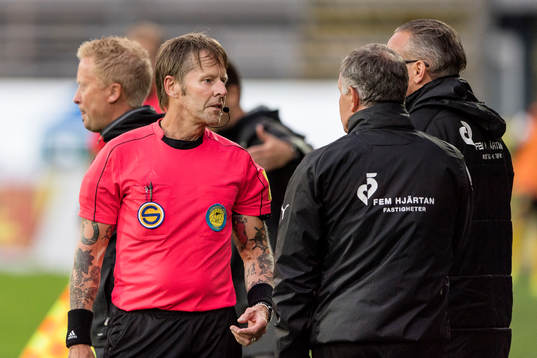 Domare Lars Olsson visar upp Halmstads tränare Jan