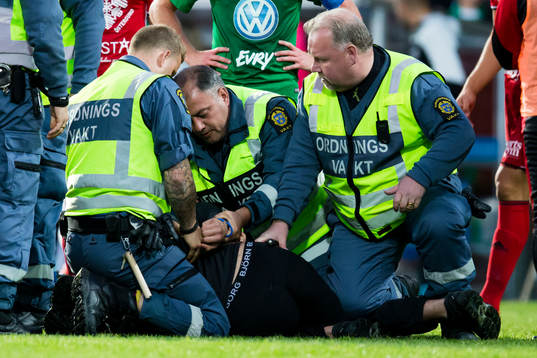 Ordningsvakter griper personen som sprang in på planen och