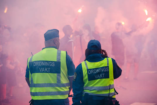 Två ordningsvakter ser IFK Göteborgs supportrar bränner