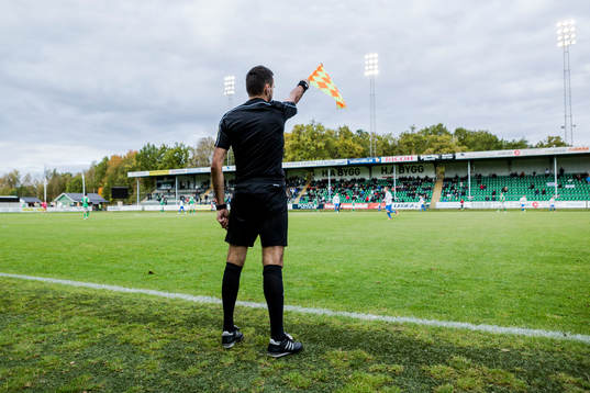 Den assisterande domaren vinkar för offside