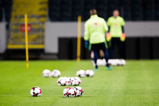 Ett antal fotbollar ligger på plan