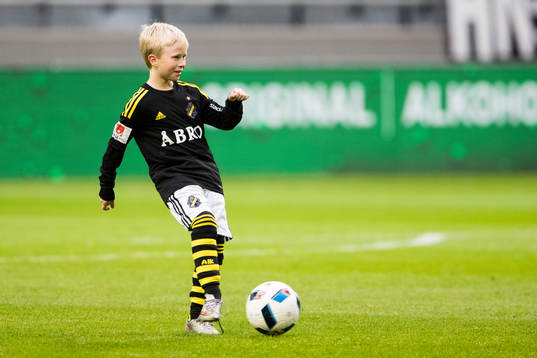 En knatte sparkar en boll innan fotbollsmatchen i