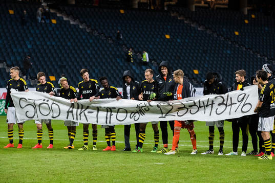 s spelare håller upp en banderoll med texten "Stöd