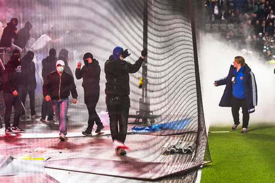 En funktionär försöker lugna ner maskerade supportrar
