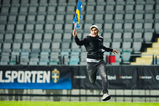 En person med svensk flagga stormar plan