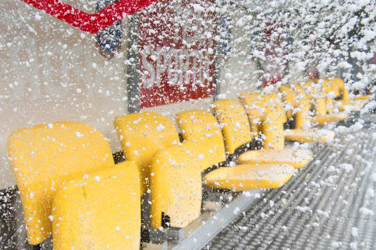 Snö på stolarna för spelarna innan fotbollsmatchen i