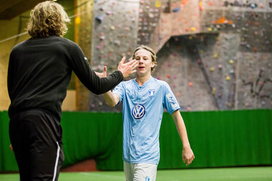 Spelare i Malmö FF gör high five med ungdomsledare