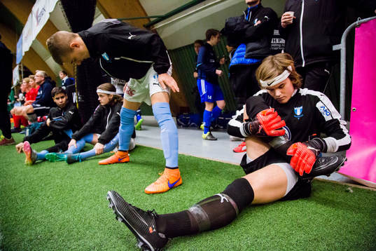 Spelare ur Malmö FF värmer upp och tittar på match