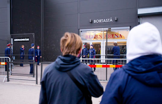 Några ungdomar tittar på Djurgårdensspelarna som värmer