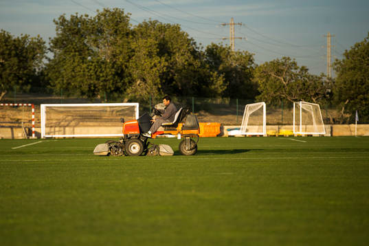 En man klipper gräset på Salou Football Center