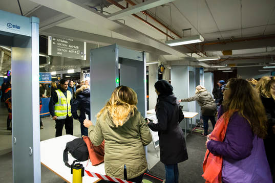 Åskådare passerar metalldetektorer