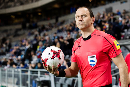 Domare Jonas Eriksson går in på plan med matchbollen