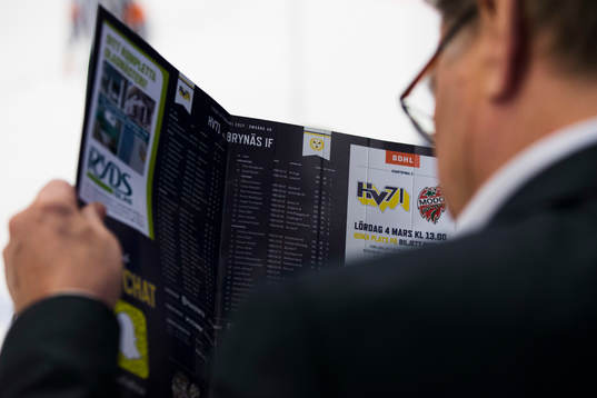 Åskådare läser i matchprogrammet