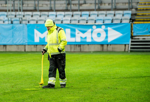 En funktionär tittar till gräset innan träningsmatchen i