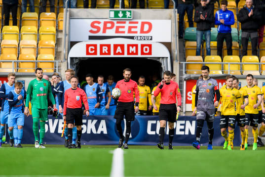 Domarna och spelarna kommer in till fotbollsmatchen i