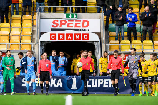 Domarna och spelarna kommer in till fotbollsmatchen i