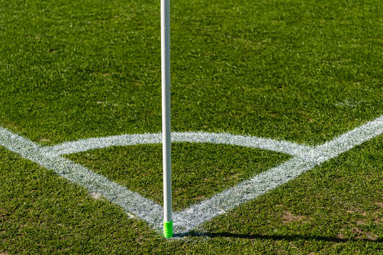 Hörnmarkering på gräsmatta före fotbollsmatchen i