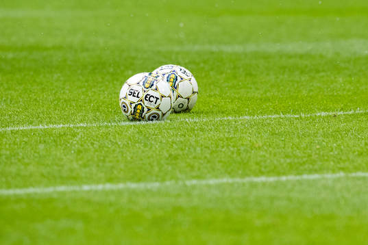 Två fotbollar ligger på gräset