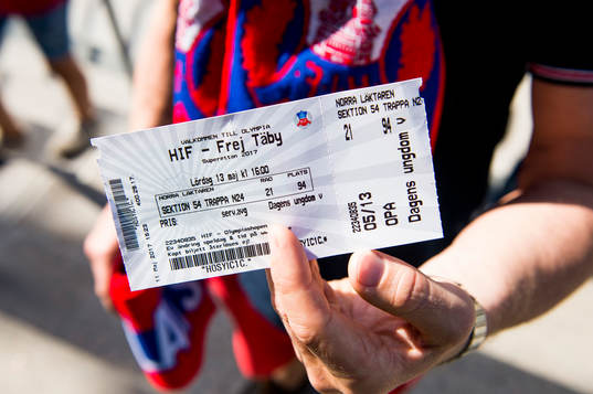 En åskådare håller upp matchbiljetten till