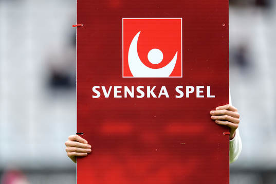 Två händer håller i portalen från Svenska Spel innan