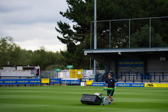 En planskötare klipper gräs på fotbollsplanen för