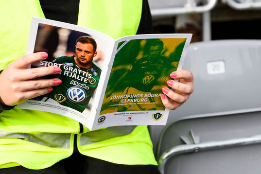 En publikvärd håller i ett matchprogram